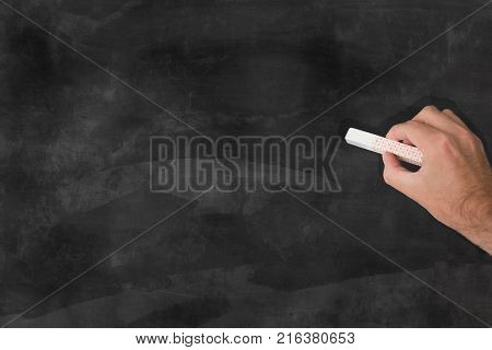 hand holding a piece of chalk in front of a blank chalkboard