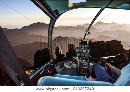 Helicopter cockpit with pilot arm and control console inside the cabin in aerial view of the holy summit of Mount Sinai, Aka Jebel Musa, 2285 meters, at sunrise, Sinai Peninsula in Egypt.