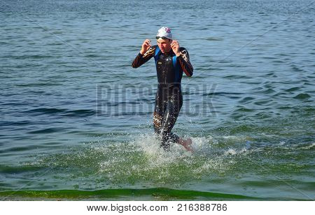 GRAFHAM, CAMBRIDGESHIRE, ENGLAND - AUGUST 06, 2017:  Leading Competitor  Leaving the water at the end of the swim.
