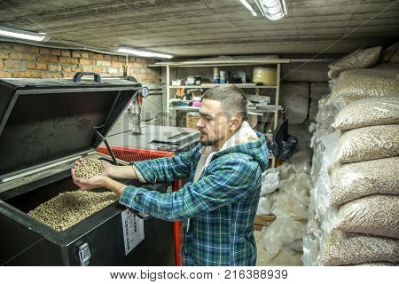 The Man Loads The Pellets In The Solid Fuel Boiler, Economical Heating