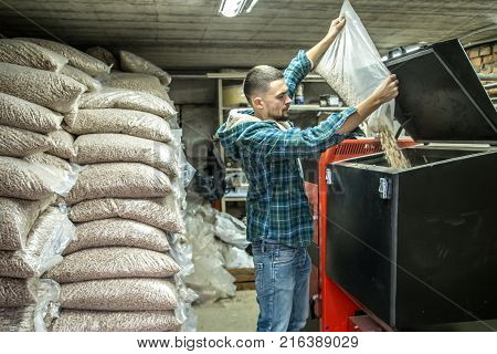 The Man Loads The Pellets In The Solid Fuel Boiler, Economical Heating