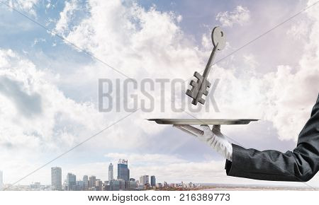 Closeup of waiter's hand in white glove presenting stone key symbol on metal tray with cityscape view on background. 3D rendering.