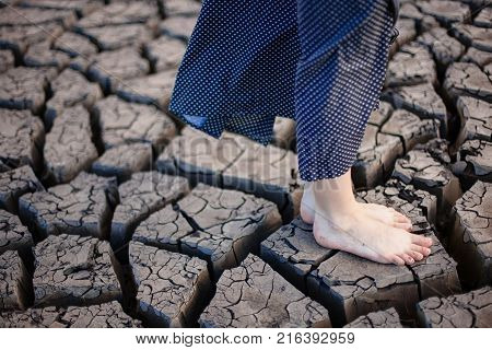 Heat shattered earth in the desert. Arid and sultry weather creates such beauty. Girl walks and stay on the cracked earth.