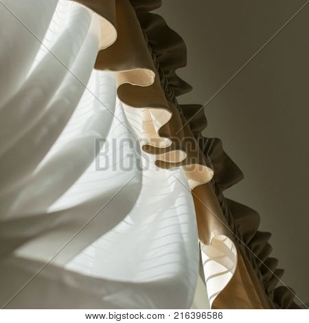 Curtain and curving valance in front of a brightly sun filled window with unusual perspective.