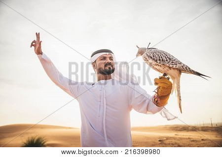 Arabian man walking in the desert at sunrise