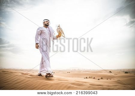 Arabian man walking in the desert at sunrise