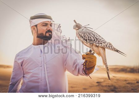 Arabian man walking in the desert at sunrise
