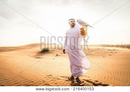 Arabian man walking in the desert at sunrise