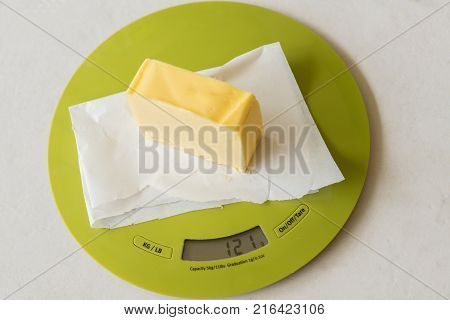 Slice of butter on greaseproof paper on digital kitchen scale