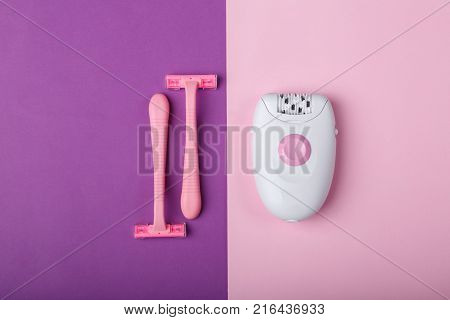 Female epilator and two disposable pink razors, lie on a pink background, free space for text.