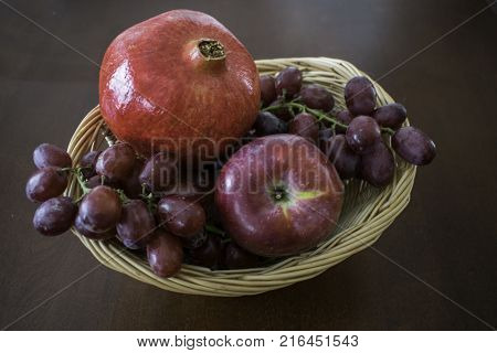 Several fruit in a wicker basket on dark wood table.