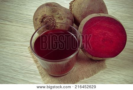 Healthy beetroot juice and fresh vegetables on wooden background.