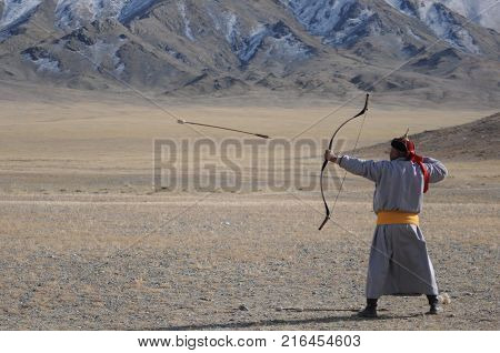 old man dressed with traditional mongolian costume compete in a boe and arrow contest during the golden eagle festival in mongolia