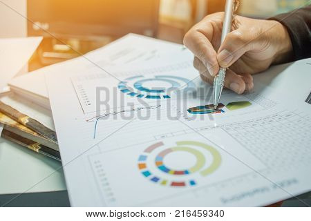 Businessman Preparing reports papers with graphs charts on Stacks of documents files for finance in office. Piles of unfinished document achieves with paper clip. Concept of Business Annual Report.