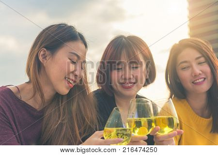 Outdoor shot of young people toasting drinks at a rooftop party. Young asian girl friends hanging out with drinks. Holiday celebration festive party. Teenage lifestyle party. Freedom and fun outdoor.