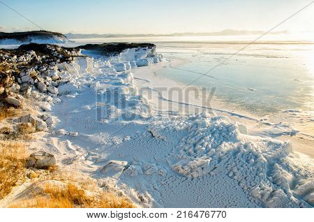 Ice floes floating on the fog water in the lake Baikal and hill, Russia. Sunset