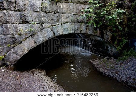 Old Stone Bridge Coverd With Moss And Torrential River.
