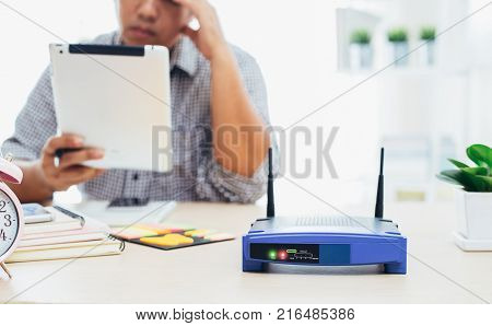 closeup of a wireless router and a man using Tablet on living room at home ofiice network lost