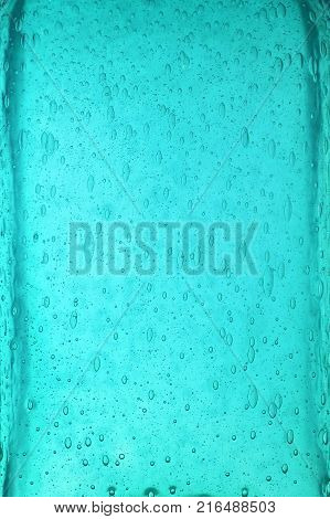 Background texture of solid transparent teal blue color glass with pattern of air bubbles, close up