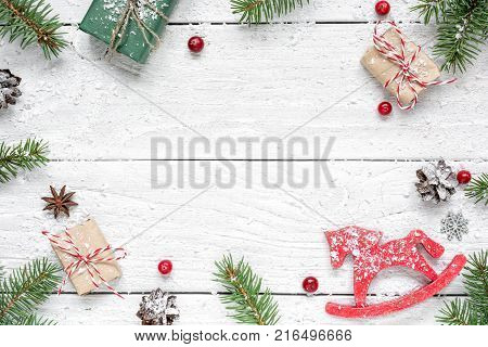 christmas composition. frame made of fir branches red berries retro christmas toy gift boxes and pine cones on white wooden table. Christmas background. Flat lay. top view with copy space