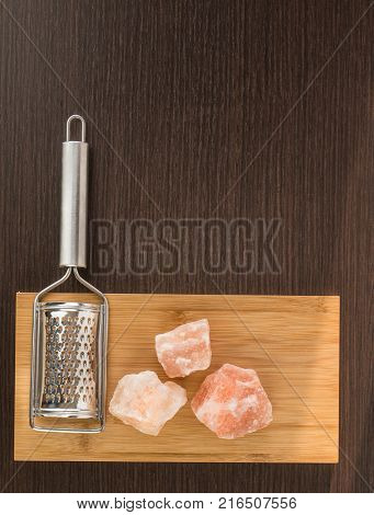 Himalayan salt with grater. Pink Himalayan salt with grinder on wooden background. Metal silver grater and red salt.