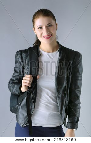Portrait of beautiful young brunette woman in stylish black jacket on gray