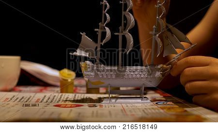 Boy hands assembling plastic model kit of ship at home. Hobby and leisure.