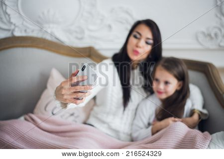 Well-groomed hand of a woman holding a phone taking a selfie with her daughter, little girl.