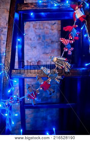 Beautiful New Year`s toys hanging on the ladder and surrounded by magical blue garland.