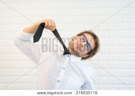 CrazyBearded Businessman Holding His Tie Hanging Himself against White Block Background.In A Moment Of Despair
