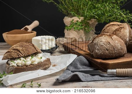 Homemade farm bread with cottage cheese curd and thyme herb malt flour and curd cream in bowl on wooden table.