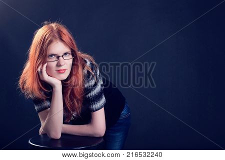 Studio portrait of the beautiful young woman with ginger hair on a dark background