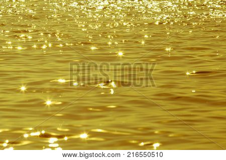 Abstract image of surface water of sea or ocean at sunset time with golden light tone.