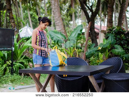 Traveler Girl Looking into her Bag on a table