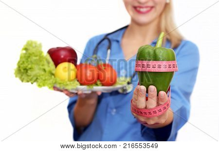 doctor dietician holds a green pepper in his hand with a measuring meter isolated on a white background