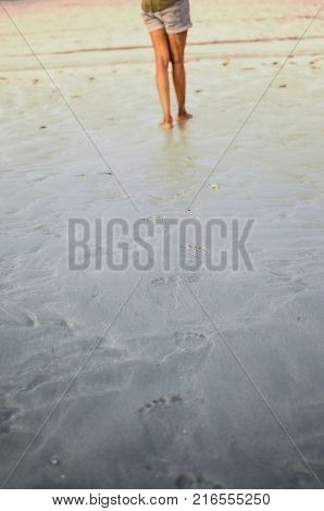 Legs with Footprints on Sand and a girl walking