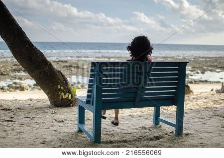 Girl Sitting Alone on a Bench near Seashore