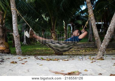 Man Sleeping on a Hammock or a net near on a Beach