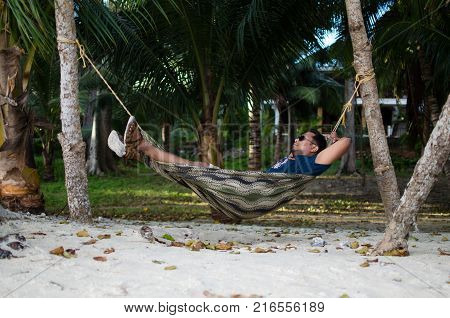 Man Sleeping on a Hammock or a net near on a Beach