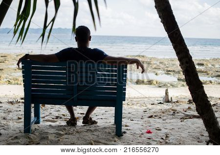 Man Sitting alone on a bench near Seashore