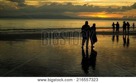 Elderly Couple Walking on a Beach In Sunset