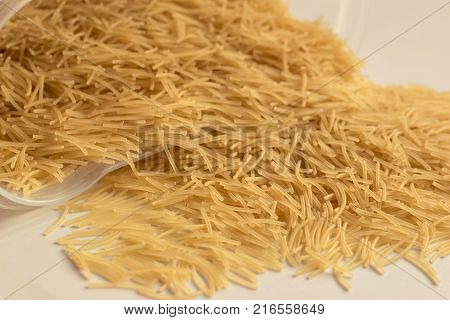 Uncooked vermicelli lying on a plate and around it close-up