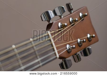 Headstock with tune machine head of acoustic six-string guitar close-up.