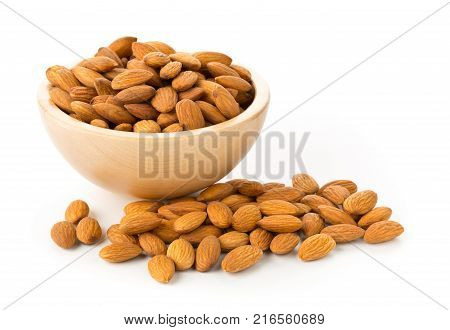 Heap of shelled almond kernels in wooden bowl over white background