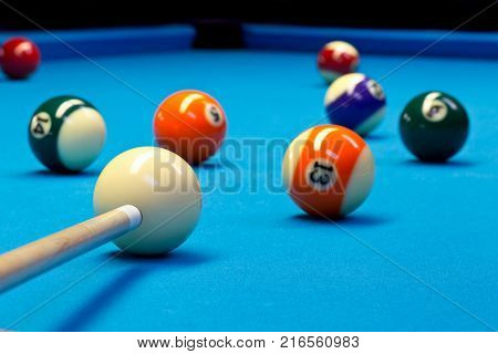 Billiard pool eightball taking the shot on billiard table with blue cloth selective focus on white ball