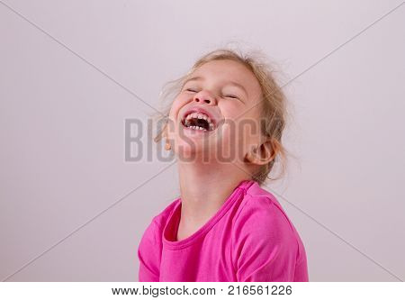 cute little girl bursts into laughter, laughs heartily on white background