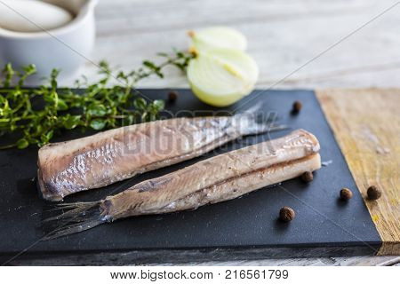 Prepared fresh salted herrings on a stone board.