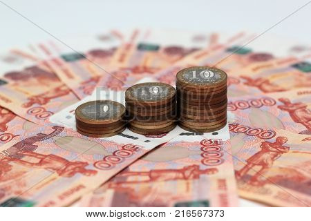 A stack of Russian commemorative ten-coins on background five-thousandth banknotes
