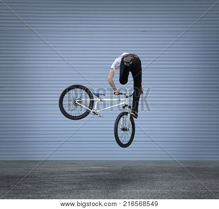 biker jumps on a bike and the background is gray architecture