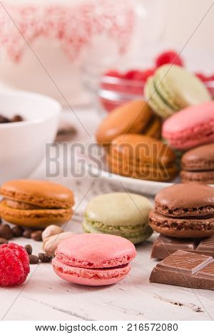 Colorful macarons with ingredients on white dish.